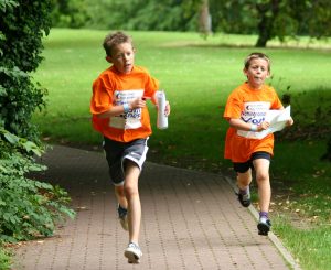 Two primary school aged boys running along a path